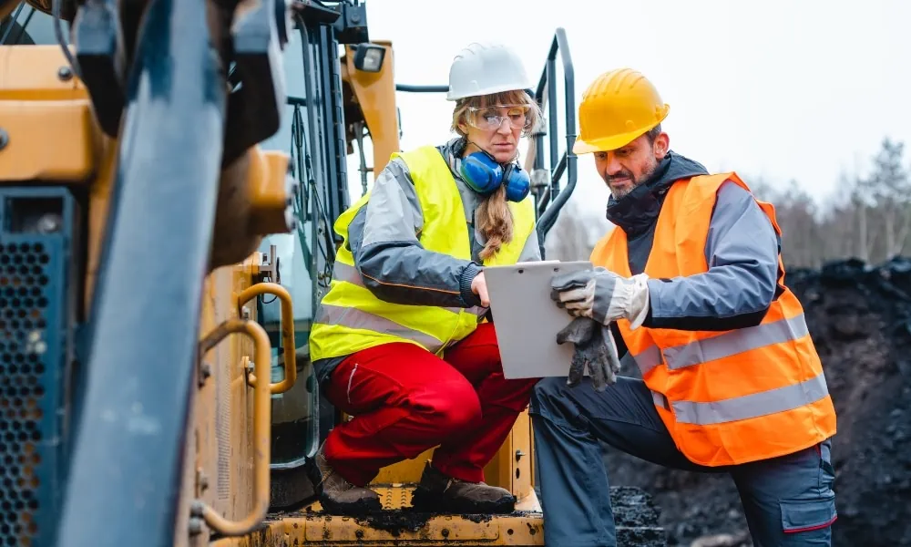 Woman speaks with her colleagues after operating an excavation machine